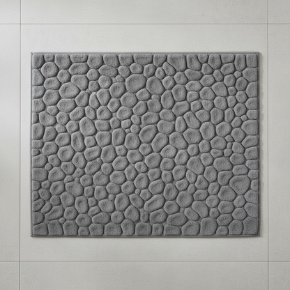Vue de dessus du tapis de bain gris à motif galets sur carrelage gris