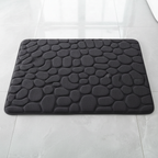 Vue de dessus du tapis de bain noir à motif galets sur carrelage gris