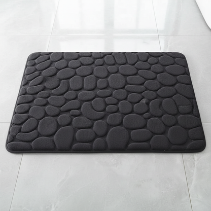 Vue de dessus du tapis de bain noir à motif galets sur carrelage gris