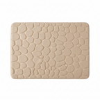 Gros plan sur la texture galets du tapis de bain beige fond blanc