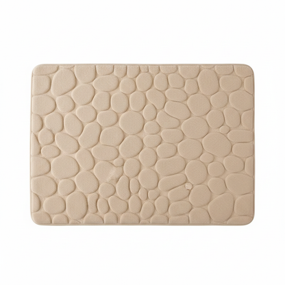 Gros plan sur la texture galets du tapis de bain beige fond blanc