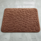Vue de dessus du tapis de bain marron à motif galets sur carrelage gris