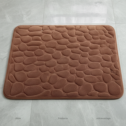 Vue de dessus du tapis de bain marron à motif galets sur carrelage gris