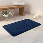 Tapis de bain bleu marine dans une ambiance spa réaliste avec marbre blanc et orchidées
