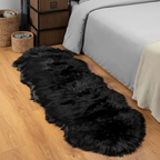 Tapis fausse fourrure noir au pied du lit sur parquet chêne dans une chambre cosy