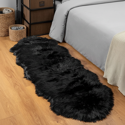 Tapis fausse fourrure noir au pied du lit sur parquet chêne dans une chambre cosy