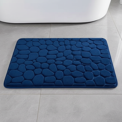 Vue de dessus du tapis de bain bleu marine à motif galets sur carrelage gris