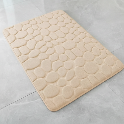 Vue de dessus du tapis de bain beige à motif galets sur carrelage gris