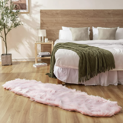 Tapis fausse fourrure rose poudré au pied du lit sur parquet chêne dans une chambre cosy